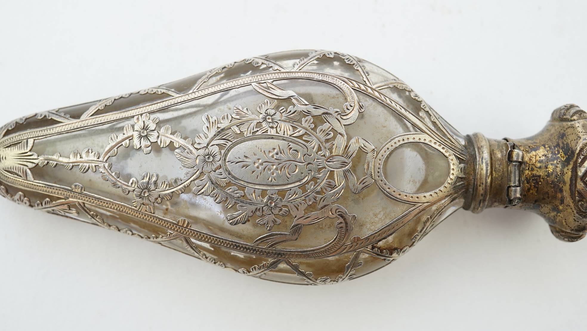 A late 19th century French parcel gilt white metal mounted and overlaid glass scent flask, with hinged cover and glass stopper